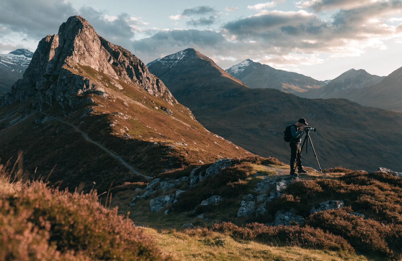 A landscape photographer on a Scottish Highland hillside at golden hour